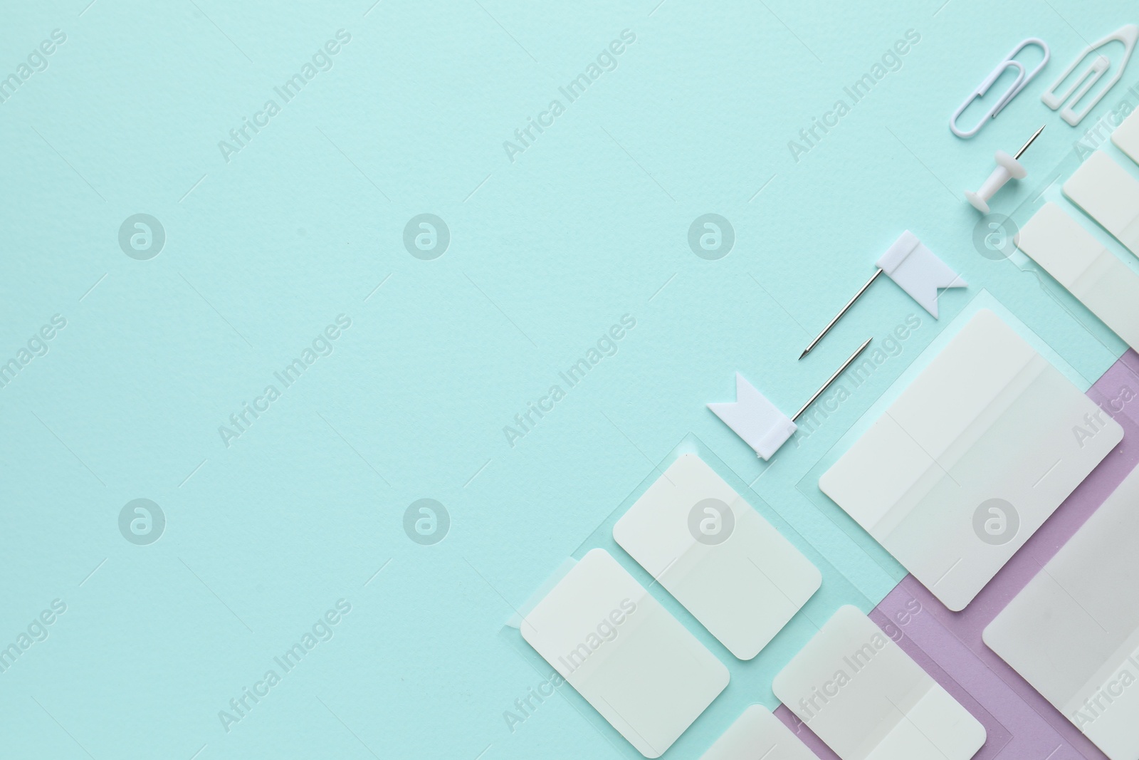 White sticky tabs and other stationery on color background, flat lay. Space for text Photo of White sticky tabs and other stationery on color background, flat lay. Space for text