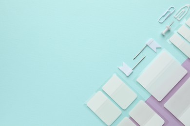Photo of White sticky tabs and other stationery on color background, flat lay. Space for text