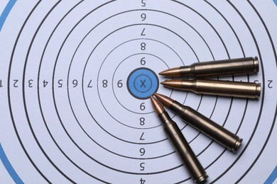 Photo of Many metal bullets on shooting target, flat lay