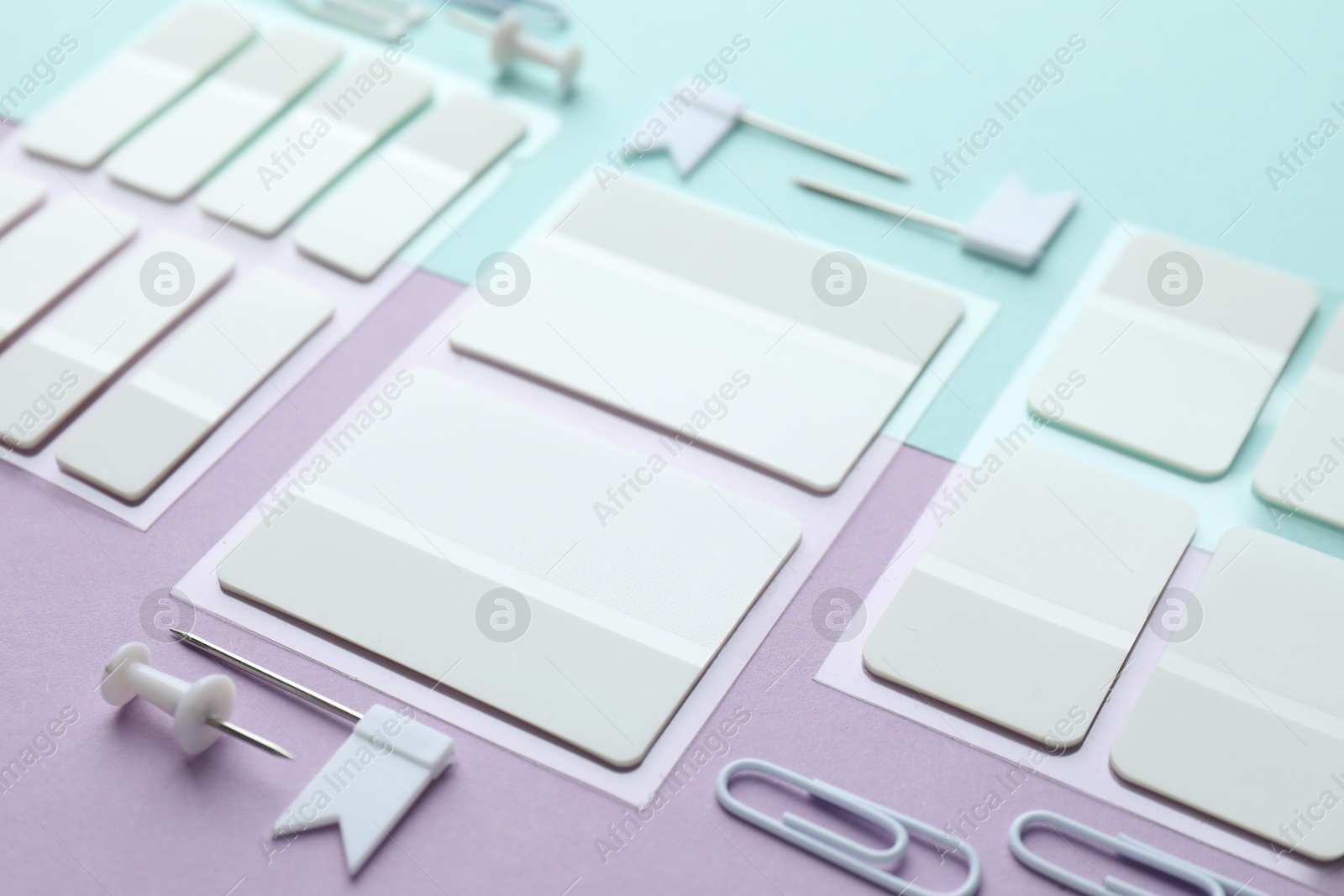 Photo of White sticky tabs and other stationery on color background, closeup