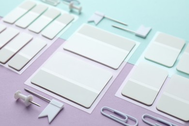 Photo of White sticky tabs and other stationery on color background, closeup