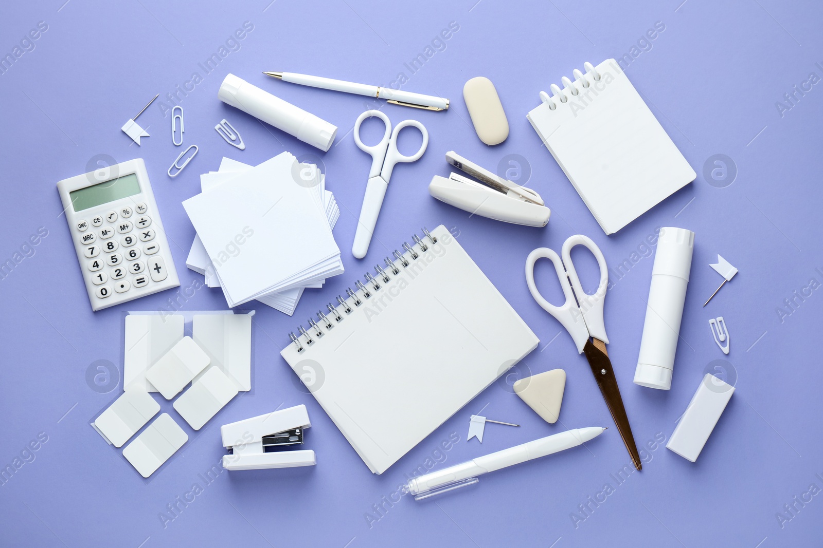 White notepad and other stationery on violet background, flat lay. Space for text Photo of White notepad and other stationery on violet background, flat lay. Space for text