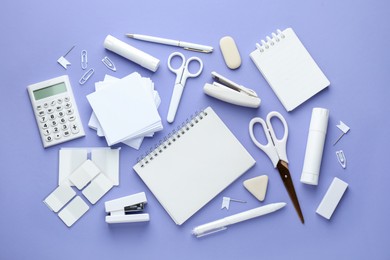 Photo of White notepad and other stationery on violet background, flat lay. Space for text