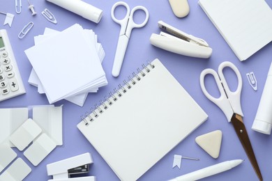 Photo of White notepad and other stationery on violet background, flat lay. Space for text