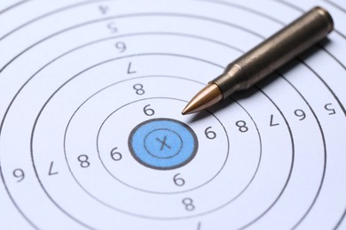 Photo of One metal bullet on shooting target, closeup