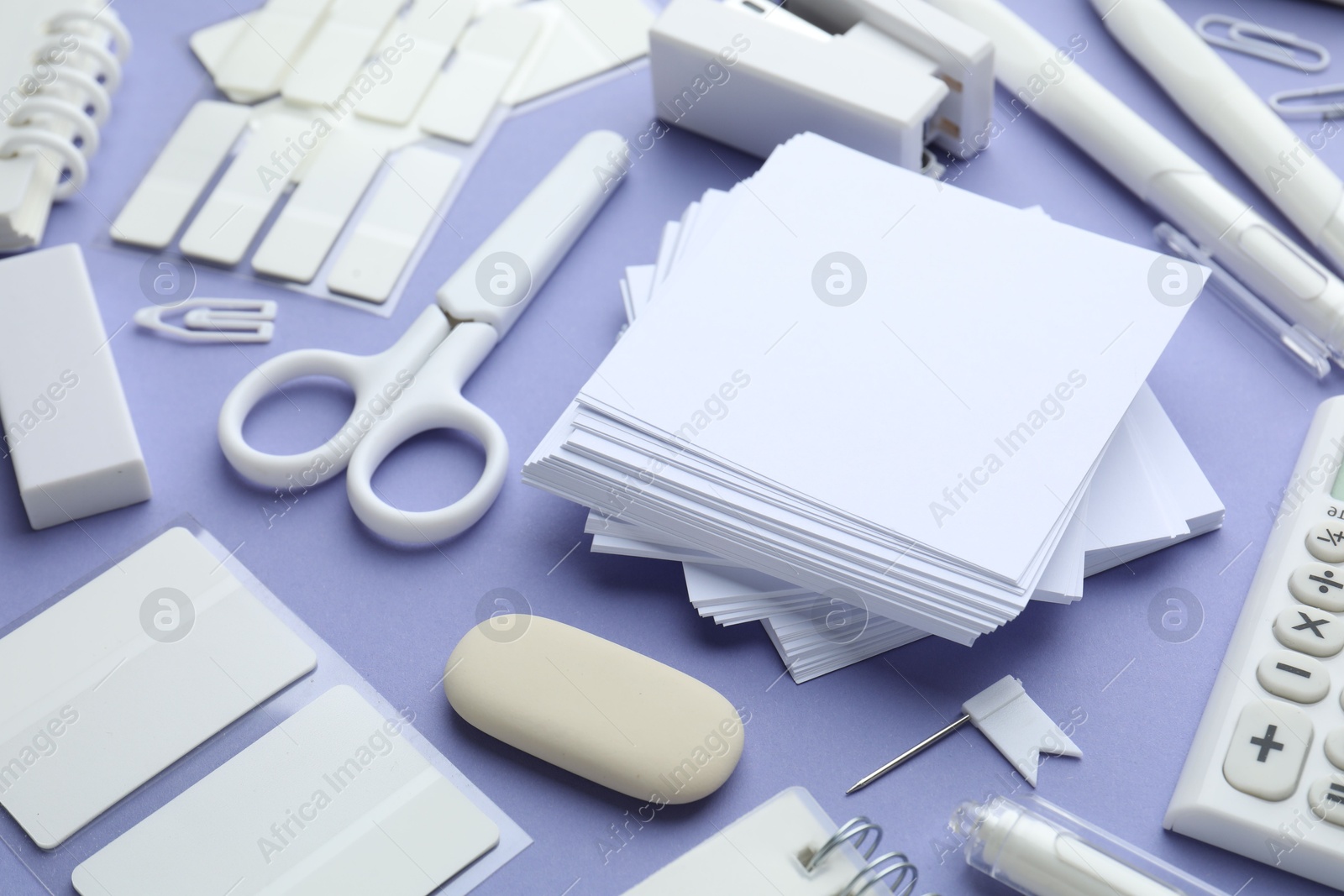 Photo of Different white stationery on violet background, closeup