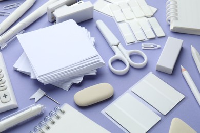 Photo of Different white stationery on violet background, closeup