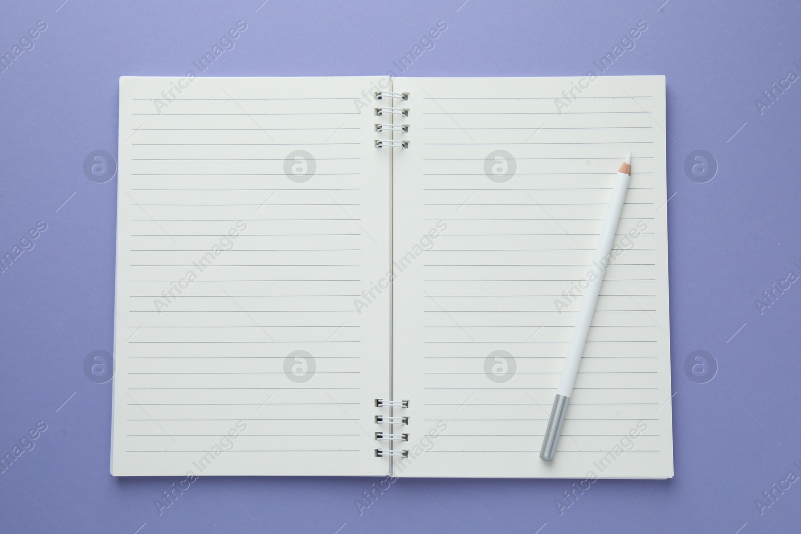 Open notepad and white pencil on violet background, top view. Space for text Photo of Open notepad and white pencil on violet background, top view. Space for text