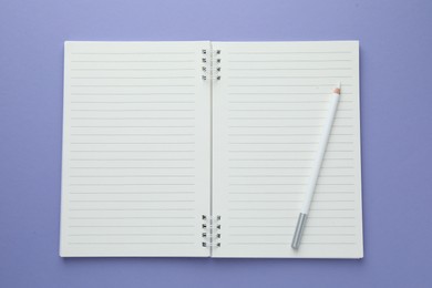Photo of Open notepad and white pencil on violet background, top view. Space for text
