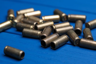 Photo of Many metal bullets on blue wooden table, closeup