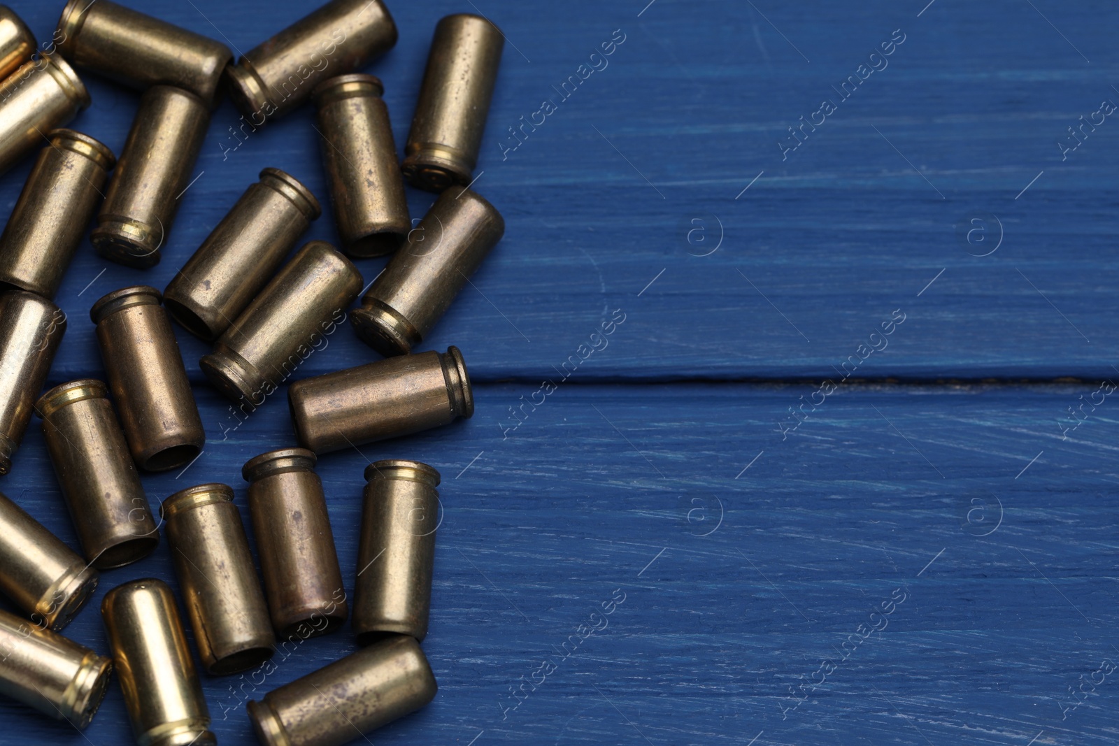 Many metal bullets on blue wooden table, flat lay. Space for text Photo of Many metal bullets on blue wooden table, flat lay. Space for text