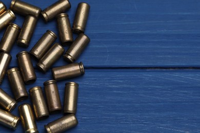 Photo of Many metal bullets on blue wooden table, flat lay. Space for text