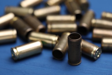 Photo of Many metal bullets on blue wooden table, closeup