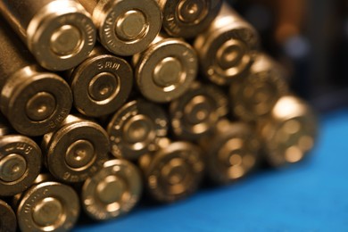 Photo of Stack of metal bullets on blue table, closeup