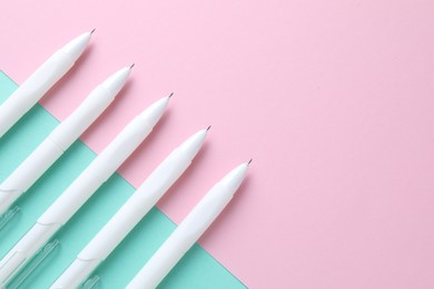 Photo of White pens on color background, flat lay. Space for text