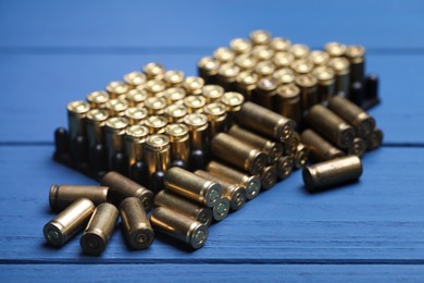Photo of Many metal bullets on blue wooden table, closeup
