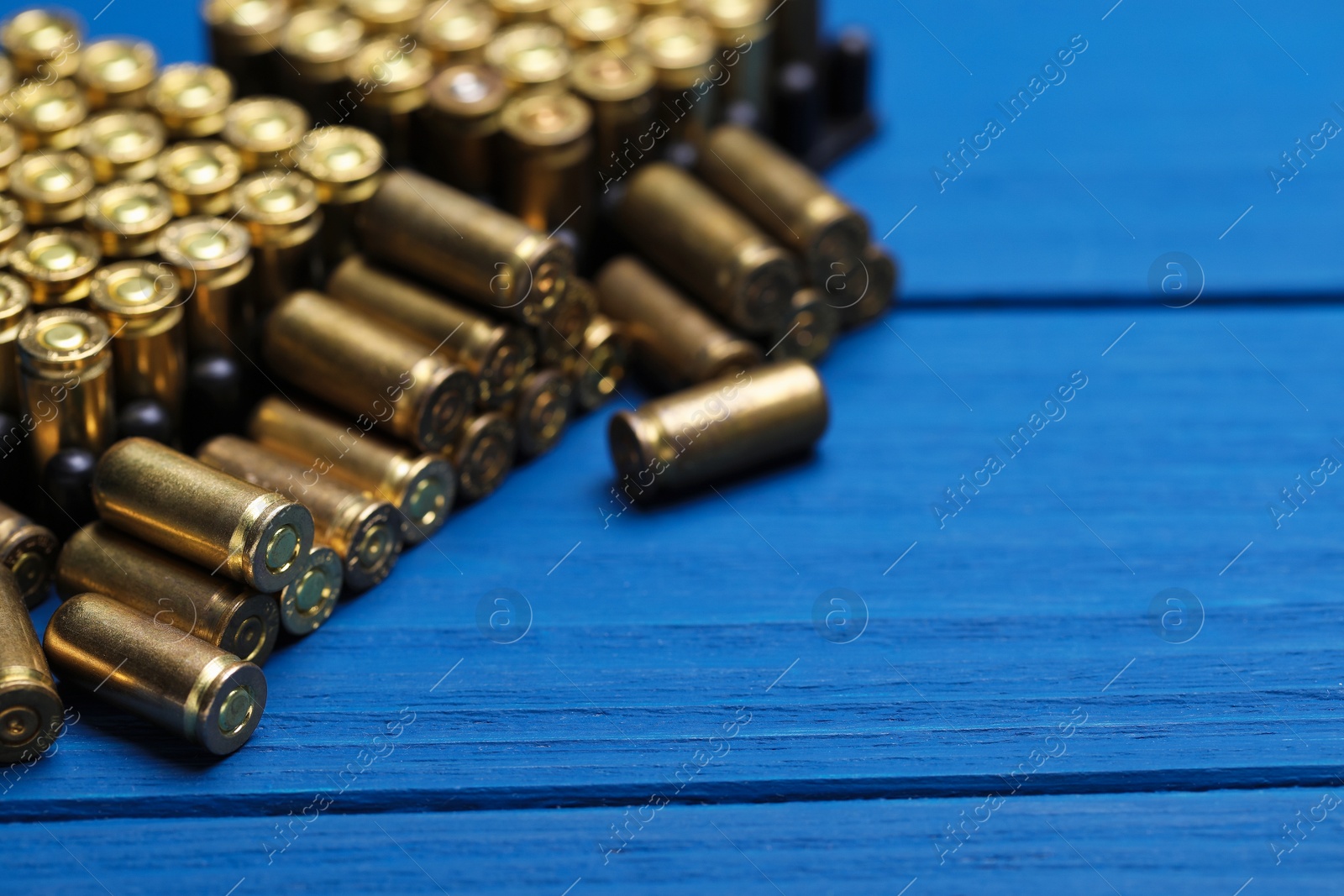 Many metal bullets on blue wooden table, closeup. Space for text Photo of Many metal bullets on blue wooden table, closeup. Space for text