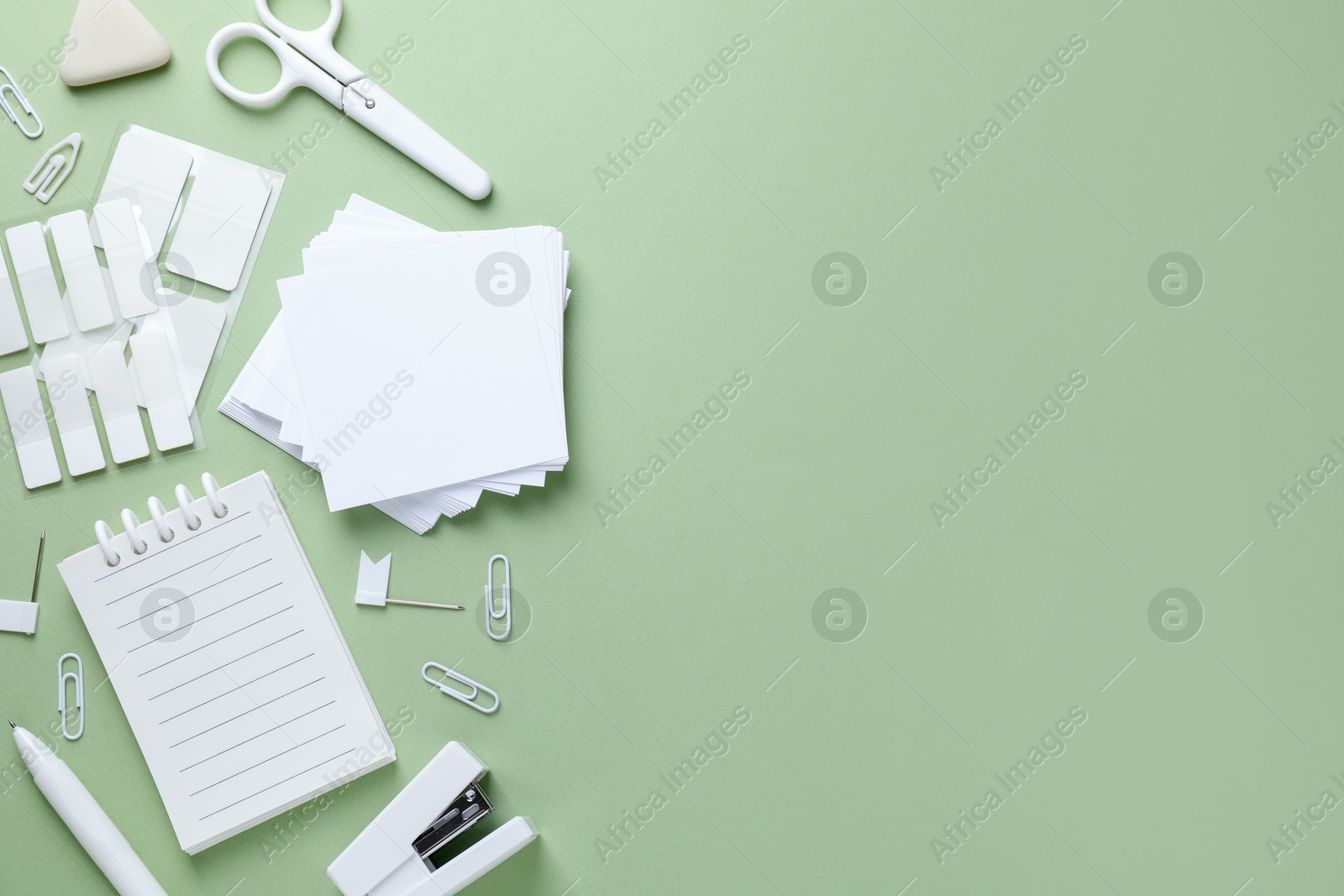 Different white stationery on light green background, flat lay. Space for text Photo of Different white stationery on light green background, flat lay. Space for text