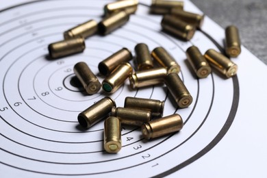 Photo of Metal bullets and shooting target on grey table, closeup