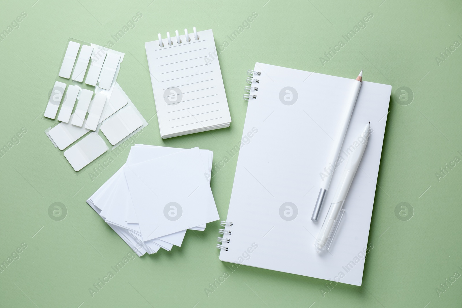 Different white stationery on light green background, flat lay Photo of Different white stationery on light green background, flat lay