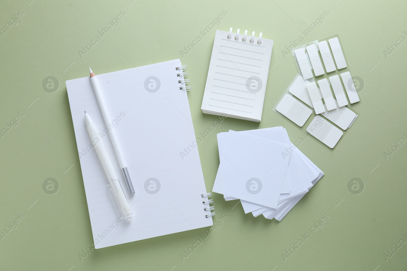 Different white stationery on light green background, flat lay Photo of Different white stationery on light green background, flat lay