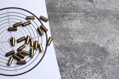 Photo of Metal bullets and shooting target on grey table, top view. Space for text