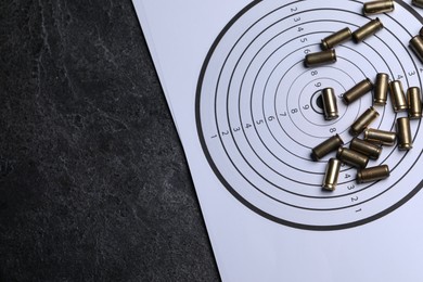 Photo of Metal bullets and shooting target on grey table, top view. Space for text
