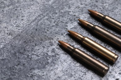 Photo of Many metal bullets on grey table, closeup. Space for text