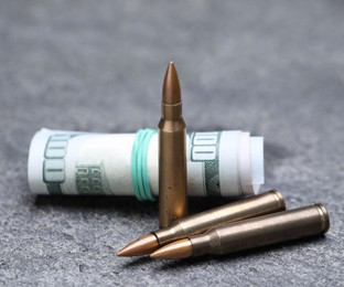 Photo of Bullets and dollars on grey table, closeup