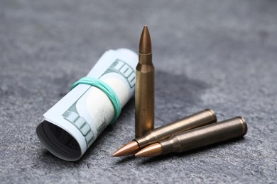 Photo of Bullets and dollars on grey table, closeup