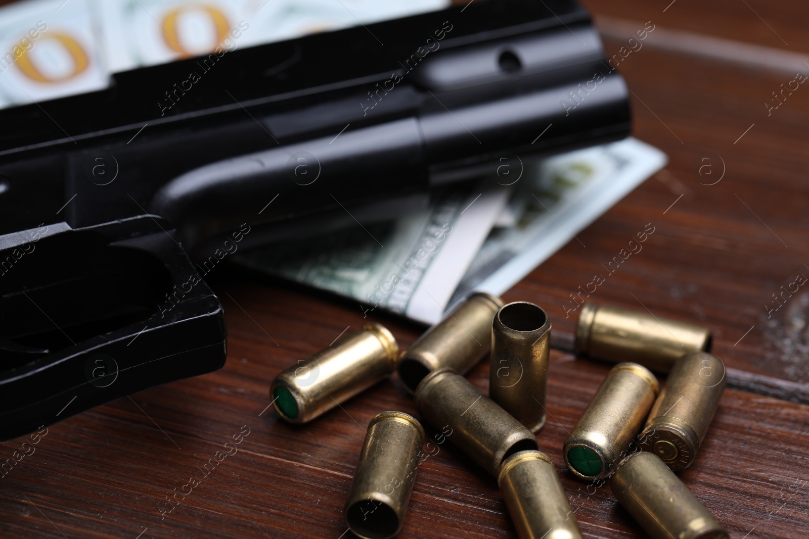Bullets, gun and dollars on wooden table, closeup Photo of Bullets, gun and dollars on wooden table, closeup