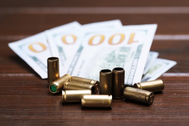 Photo of Bullets and dollars on wooden table, closeup