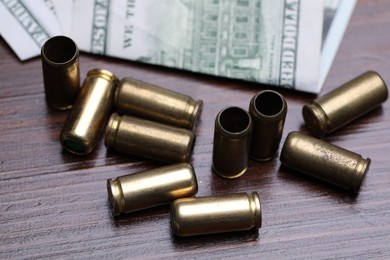 Photo of Bullets and dollars on wooden table, closeup