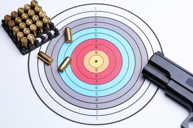 Photo of Many metal bullets and gun on shooting target, above view