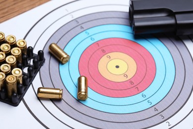 Photo of Metal bullets, gun and shooting target on table, closeup