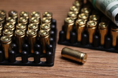 Photo of Bullets and dollars on wooden table, closeup