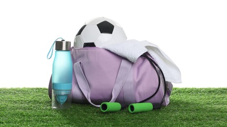 Photo of Stylish gym bag with sports equipment, towel and bottle on green grass against white background
