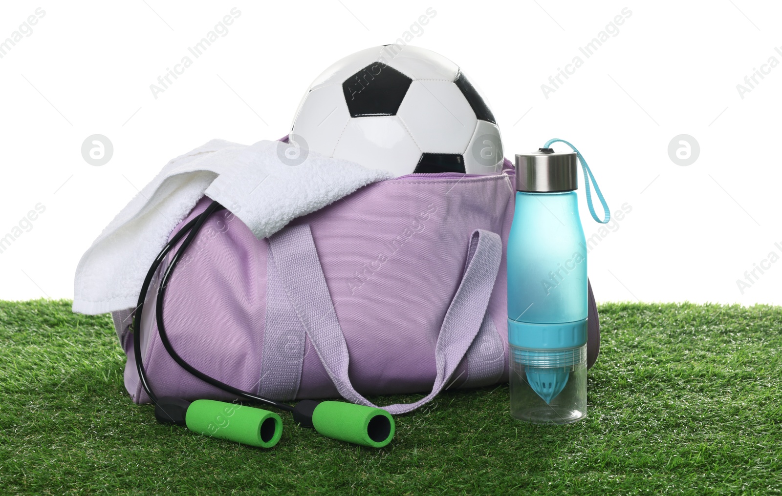 Photo of Stylish gym bag with sports equipment, towel and bottle on green grass against white background