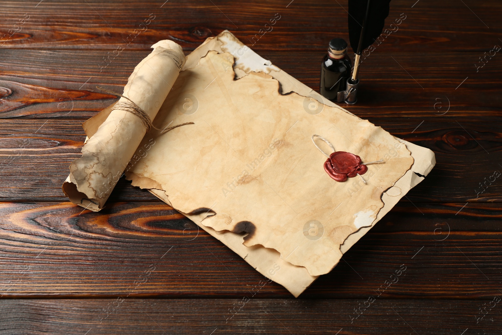 Old paper scrolls, feather and inkwell on wooden table Photo of Old paper scrolls, feather and inkwell on wooden table