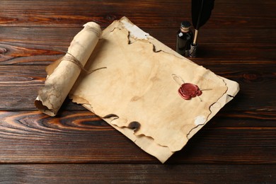 Photo of Old paper scrolls, feather and inkwell on wooden table