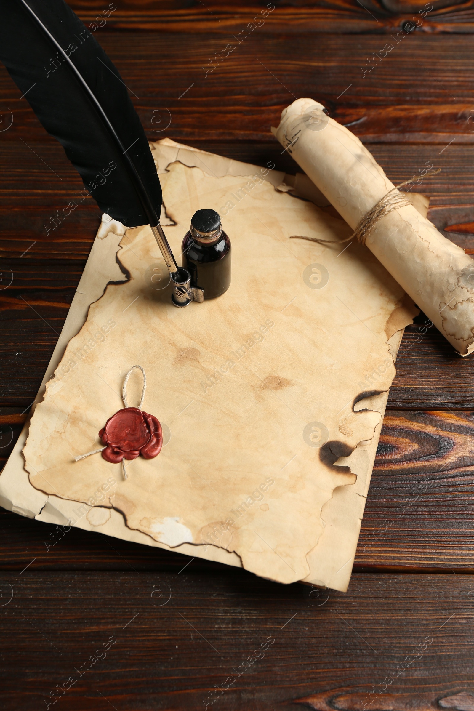 Old paper scrolls, feather and inkwell on wooden table, above view Photo of Old paper scrolls, feather and inkwell on wooden table, above view