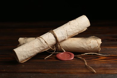 Photo of Old rolled paper scrolls on wooden table, closeup