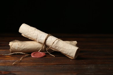 Photo of Old rolled paper scrolls on wooden table, closeup