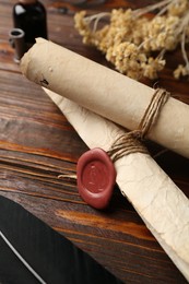 Photo of Old paper scrolls and feather on wooden table, closeup