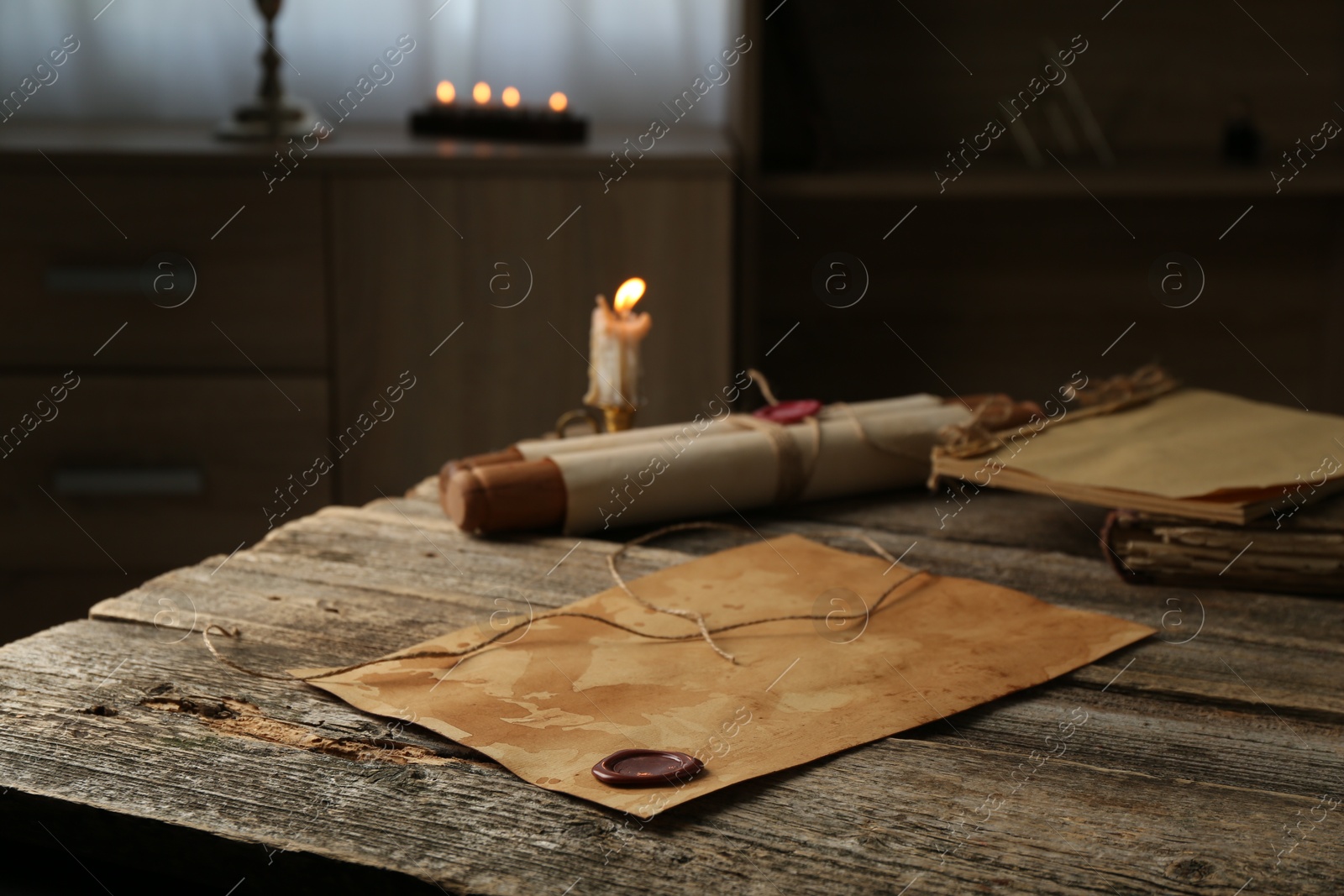 Old paper scrolls and burning candle on wooden table, closeup Photo of Old paper scrolls and burning candle on wooden table, closeup