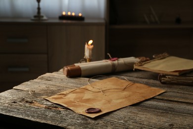 Photo of Old paper scrolls and burning candle on wooden table, closeup