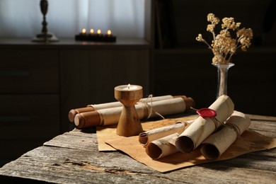 Photo of Old paper scrolls and burning candle on wooden table