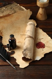 Photo of Paper scrolls, burning candle, feather, inkwell and books on wooden table, closeup
