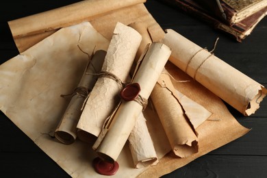 Photo of Many old rolled scrolls on black wooden table, closeup