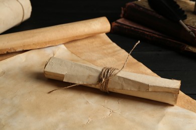 Photo of Many old rolled scrolls and books on black wooden table, closeup